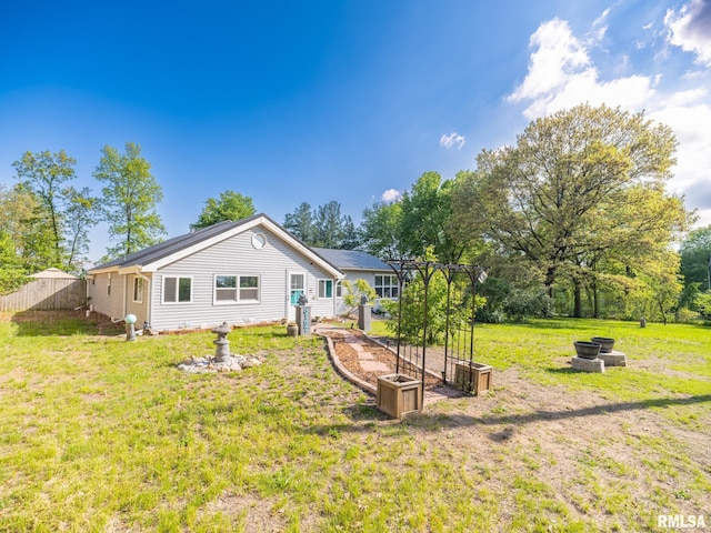 rear view of house with a yard and fence
