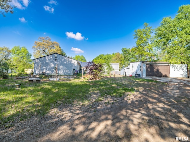 view of yard featuring an outbuilding, driveway, fence, and a garage
