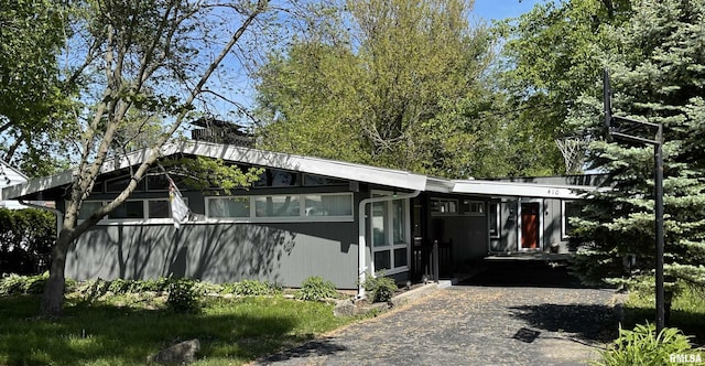 mid-century inspired home featuring gravel driveway and a carport