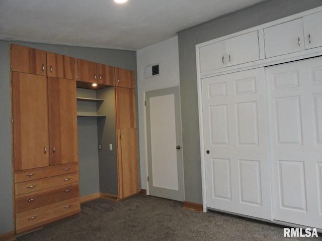 unfurnished bedroom with dark carpet, baseboards, and a closet