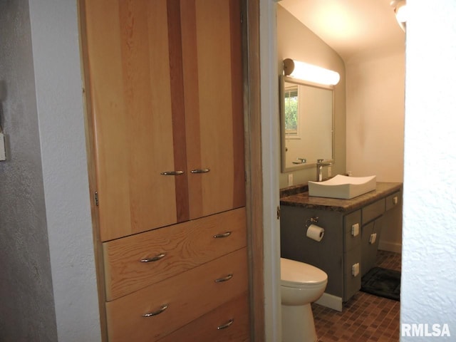half bathroom with toilet, vanity, and vaulted ceiling