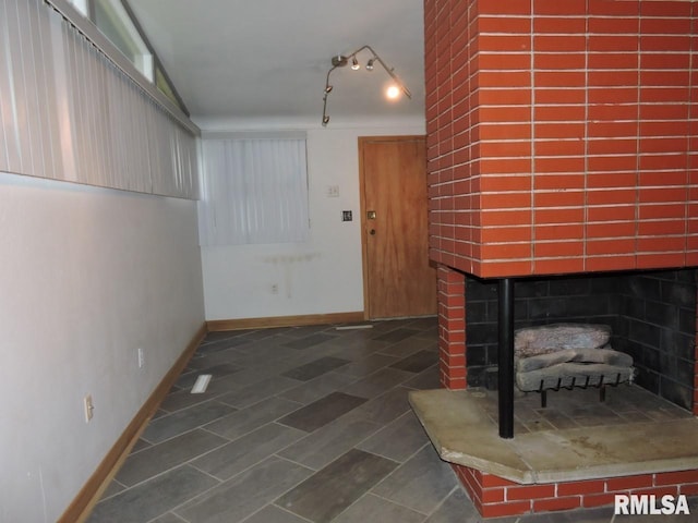 entryway featuring a fireplace with raised hearth and baseboards