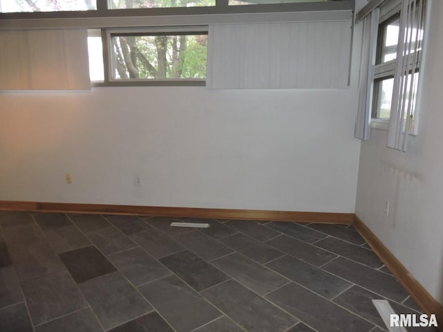 unfurnished room featuring healthy amount of natural light and baseboards