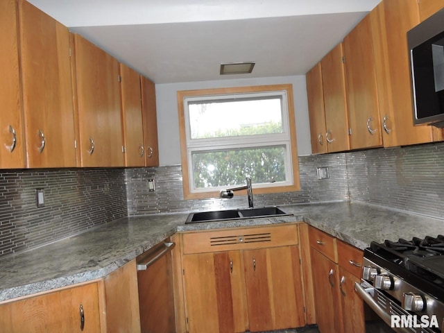 kitchen featuring a sink, appliances with stainless steel finishes, brown cabinets, and decorative backsplash
