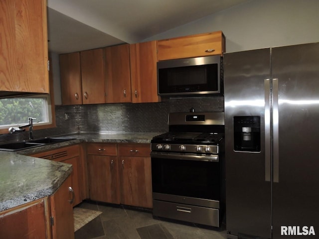 kitchen with stainless steel appliances, a sink, decorative backsplash, brown cabinets, and lofted ceiling