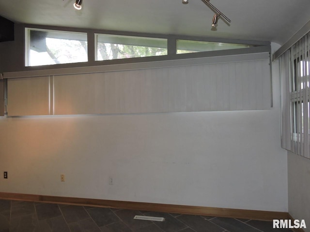 spare room featuring baseboards and track lighting