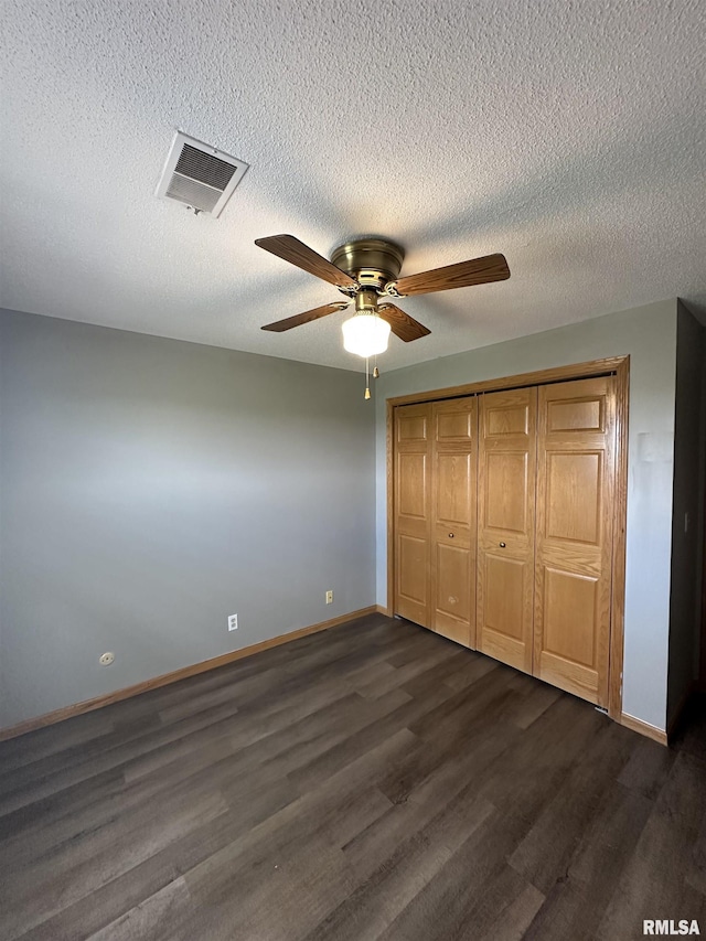 unfurnished bedroom with ceiling fan, visible vents, dark wood finished floors, baseboards, and a closet