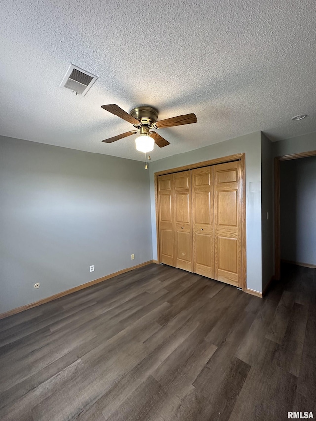 unfurnished bedroom with baseboards, visible vents, dark wood finished floors, and a closet