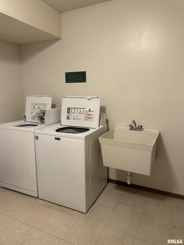 laundry area featuring separate washer and dryer, a sink, baseboards, and light tile patterned floors