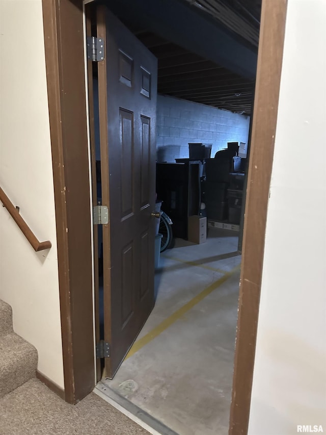 hallway featuring stairs, concrete block wall, and concrete flooring
