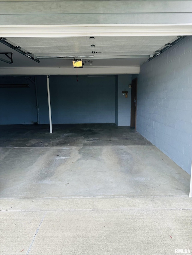 garage featuring a garage door opener and concrete block wall