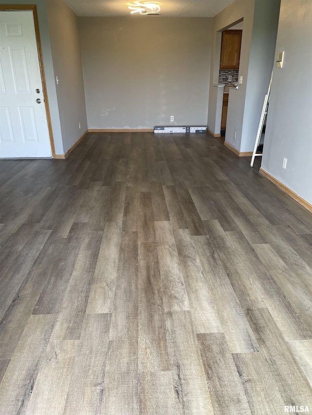 spare room with baseboards and dark wood-style floors