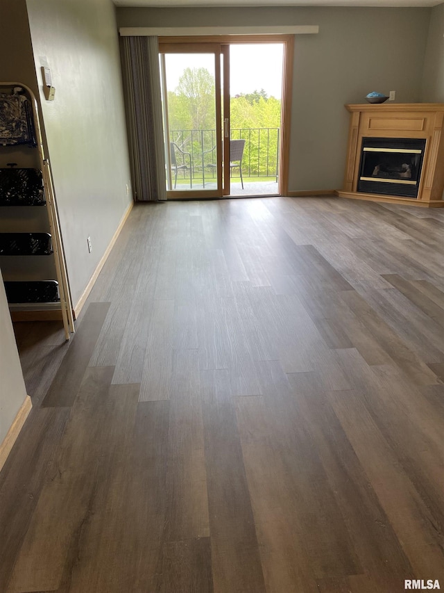 unfurnished living room featuring baseboards, a glass covered fireplace, and wood finished floors