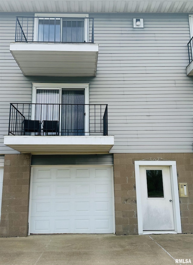 rear view of property with an attached garage, driveway, and a balcony