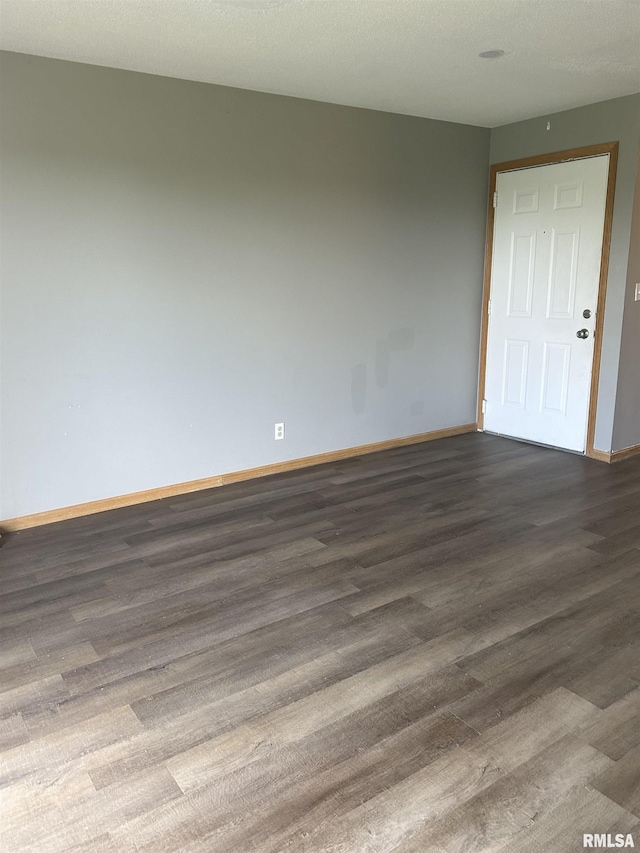 spare room featuring baseboards and dark wood-style floors