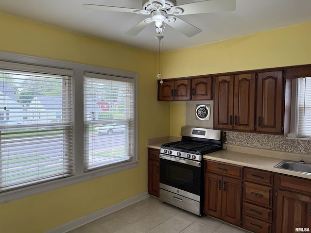 kitchen featuring light countertops, a sink, ceiling fan, and gas range