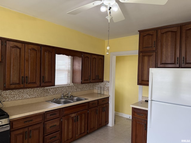 kitchen featuring a sink, light countertops, freestanding refrigerator, a ceiling fan, and decorative backsplash