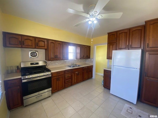 kitchen with freestanding refrigerator, a sink, stainless steel gas range oven, and light countertops