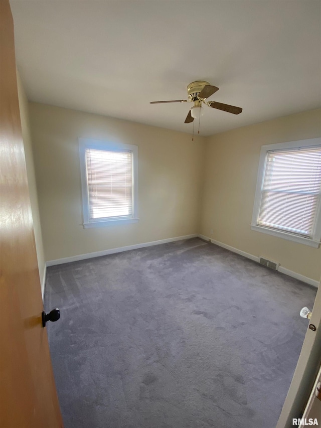 carpeted spare room with baseboards, visible vents, and ceiling fan