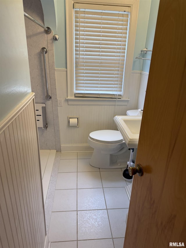 full bath featuring tile patterned flooring, wainscoting, walk in shower, and toilet