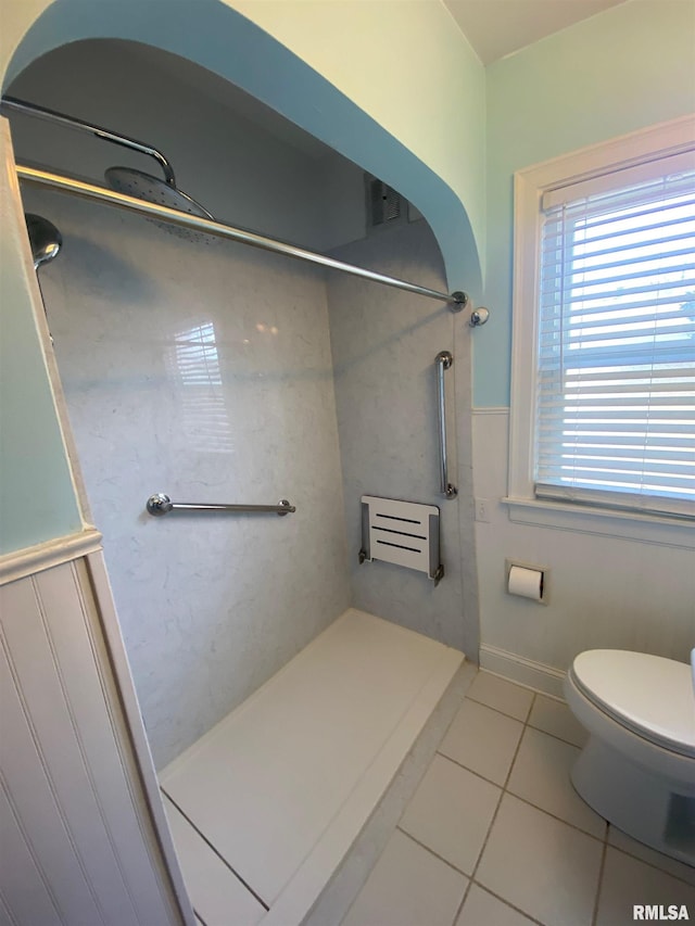 full bathroom with tile patterned floors, a wainscoted wall, walk in shower, and toilet