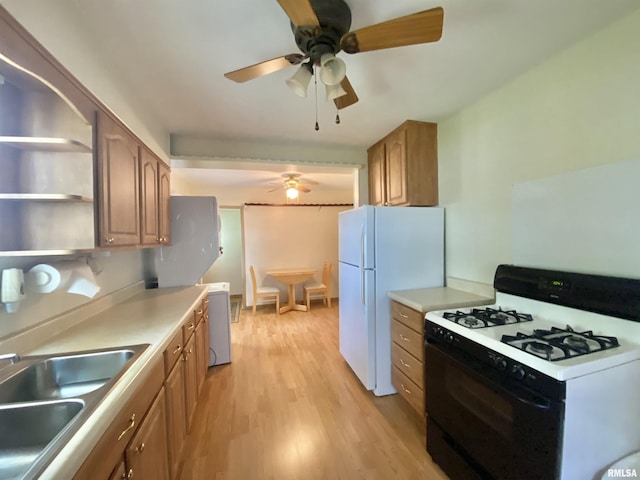 kitchen featuring freestanding refrigerator, light wood finished floors, gas stove, ceiling fan, and a sink