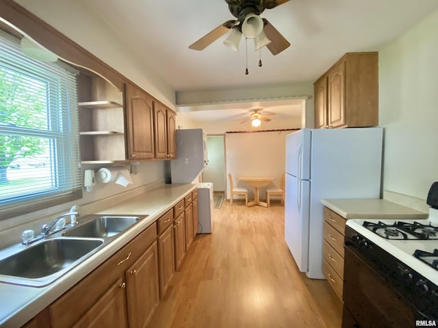 kitchen with brown cabinetry, gas stove, ceiling fan, a sink, and light wood-type flooring