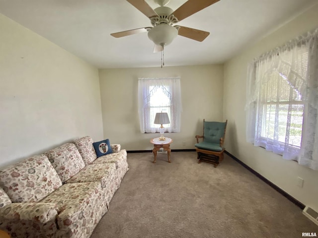 living area featuring baseboards, carpet flooring, visible vents, and ceiling fan