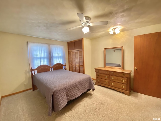bedroom with a closet, light carpet, baseboards, and a ceiling fan