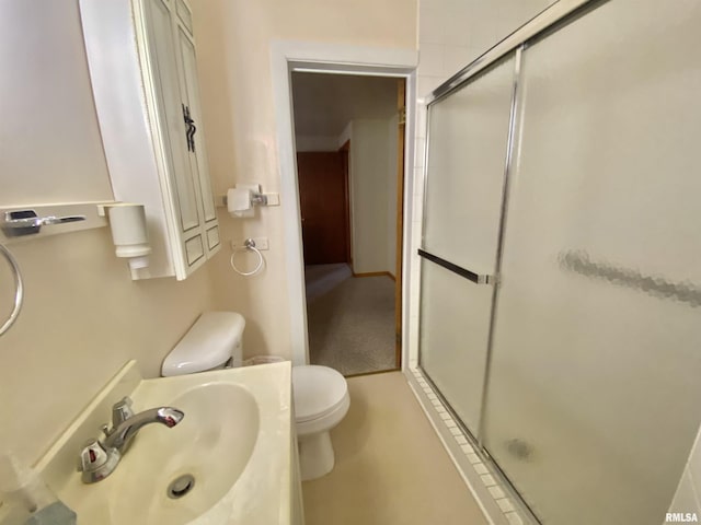 bathroom featuring toilet, vanity, and a shower stall