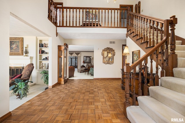 foyer featuring baseboards, stairs, visible vents, and a high ceiling