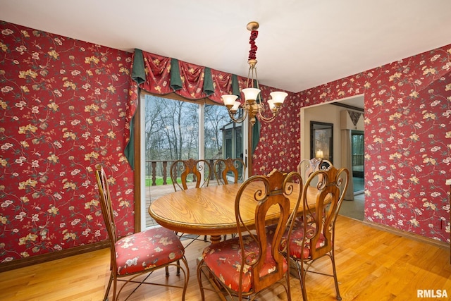dining space featuring baseboards, light wood-style floors, an inviting chandelier, and wallpapered walls