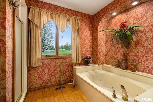 bathroom with wallpapered walls, baseboards, wood finished floors, an enclosed shower, and a tub with jets