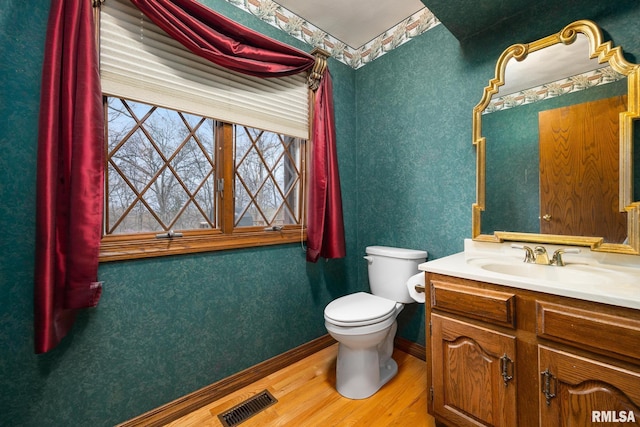 bathroom featuring toilet, wood finished floors, visible vents, baseboards, and vanity
