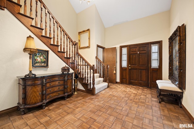 entrance foyer featuring stairway, baseboards, and a towering ceiling