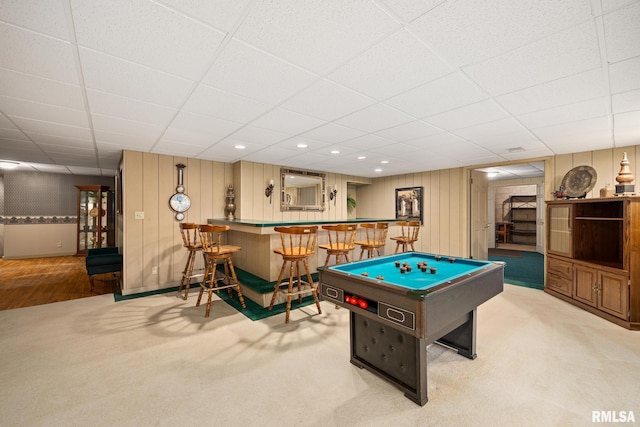recreation room featuring carpet floors, indoor bar, and a drop ceiling