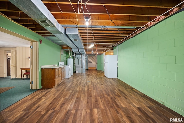 basement with freestanding refrigerator, water heater, dark wood-type flooring, visible vents, and concrete block wall