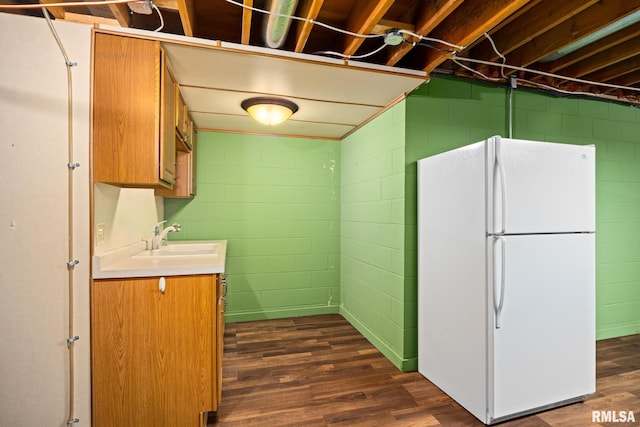 kitchen with a sink, brown cabinetry, freestanding refrigerator, dark wood finished floors, and light countertops
