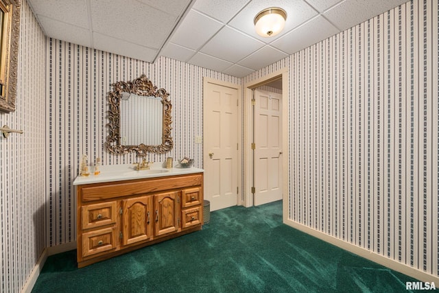 bathroom featuring a drop ceiling, wallpapered walls, and carpet floors