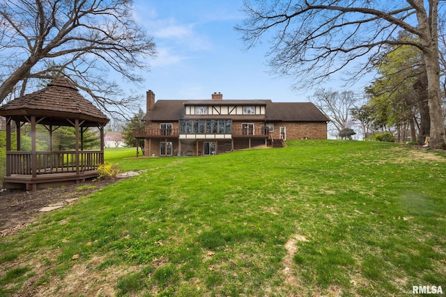rear view of property featuring a gazebo, a deck, a chimney, and a lawn