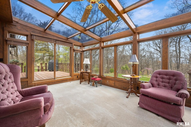 sunroom / solarium featuring carpet flooring, wood walls, and ceiling fan