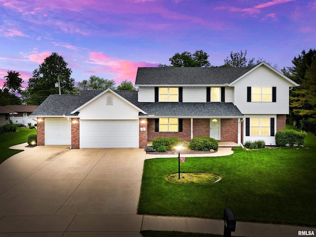 traditional-style house with a garage, driveway, a yard, and brick siding