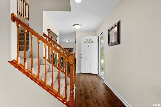 foyer featuring dark wood-style floors, stairway, and baseboards