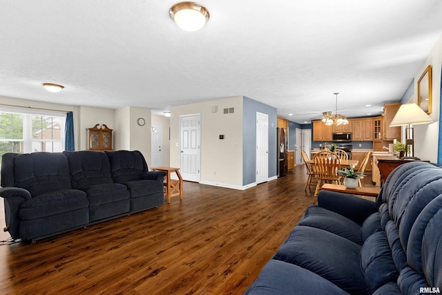 living area with a chandelier, dark wood finished floors, and baseboards