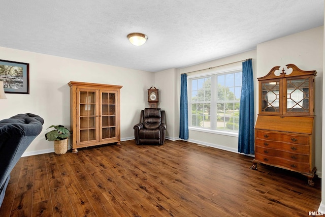 living area with dark wood finished floors, baseboards, and a textured ceiling