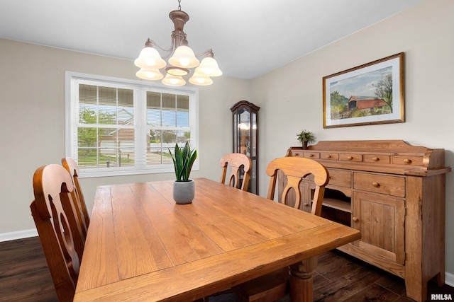 dining area featuring a chandelier, dark wood-style flooring, and baseboards