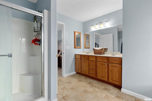 full bath with baseboards, a stall shower, double vanity, and stone finish flooring