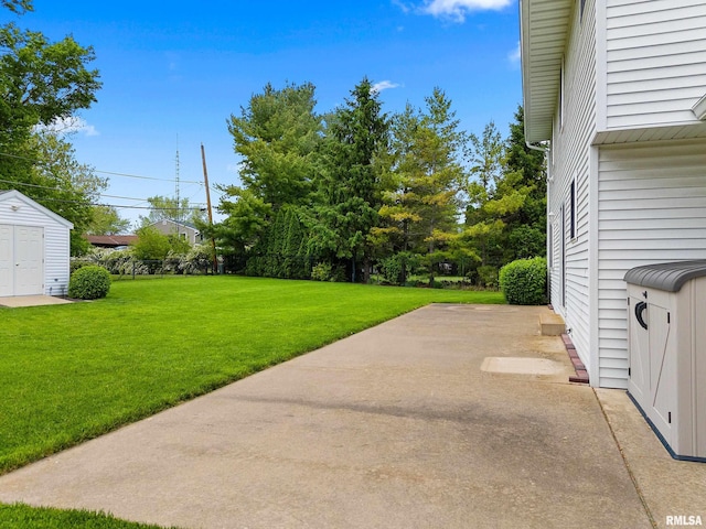 view of green lawn featuring a patio, a storage unit, and an outdoor structure