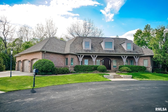 view of front facade featuring a front yard, a shingled roof, brick siding, and a garage