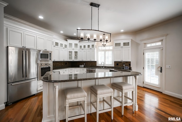 kitchen featuring a sink, stainless steel appliances, dark wood-style flooring, decorative backsplash, and ornamental molding